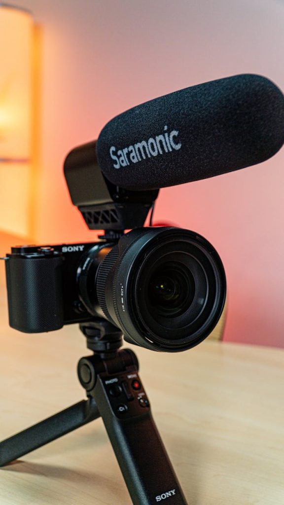 Vertical shot of a professional video camera with Saramonic microphone on a tripod indoors.